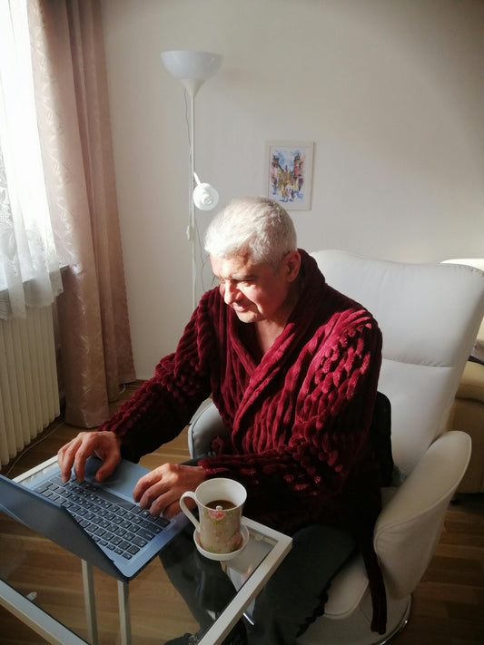 Older man with a cup of coffee researching on a laptop