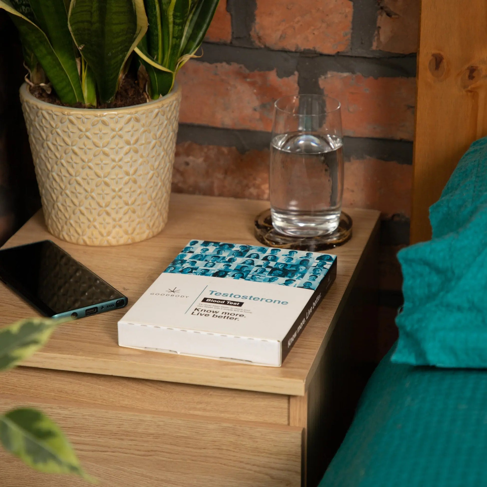 Testosterone Blood test on Nightstand with books, a glass of water, and a phone against a brick wall.